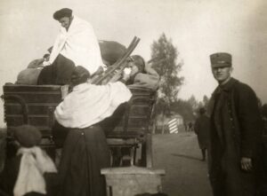 oude vergeelde foto waarop een gezin op een huifkar te zien is. In de kar oma en kleindochter. voor de kar, vader, moeder en zoontje.