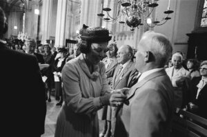 zwart wit foto met op de voorgrond koningin Beatrix die een onderscheiding opspeld bij een veteraan. 