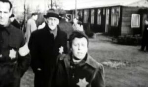 Zwart/wit foto met mensen in kamp westerbork er op, ze dragen de karakteristieke gestreepte pakken en jodensterren op hun kleding. 